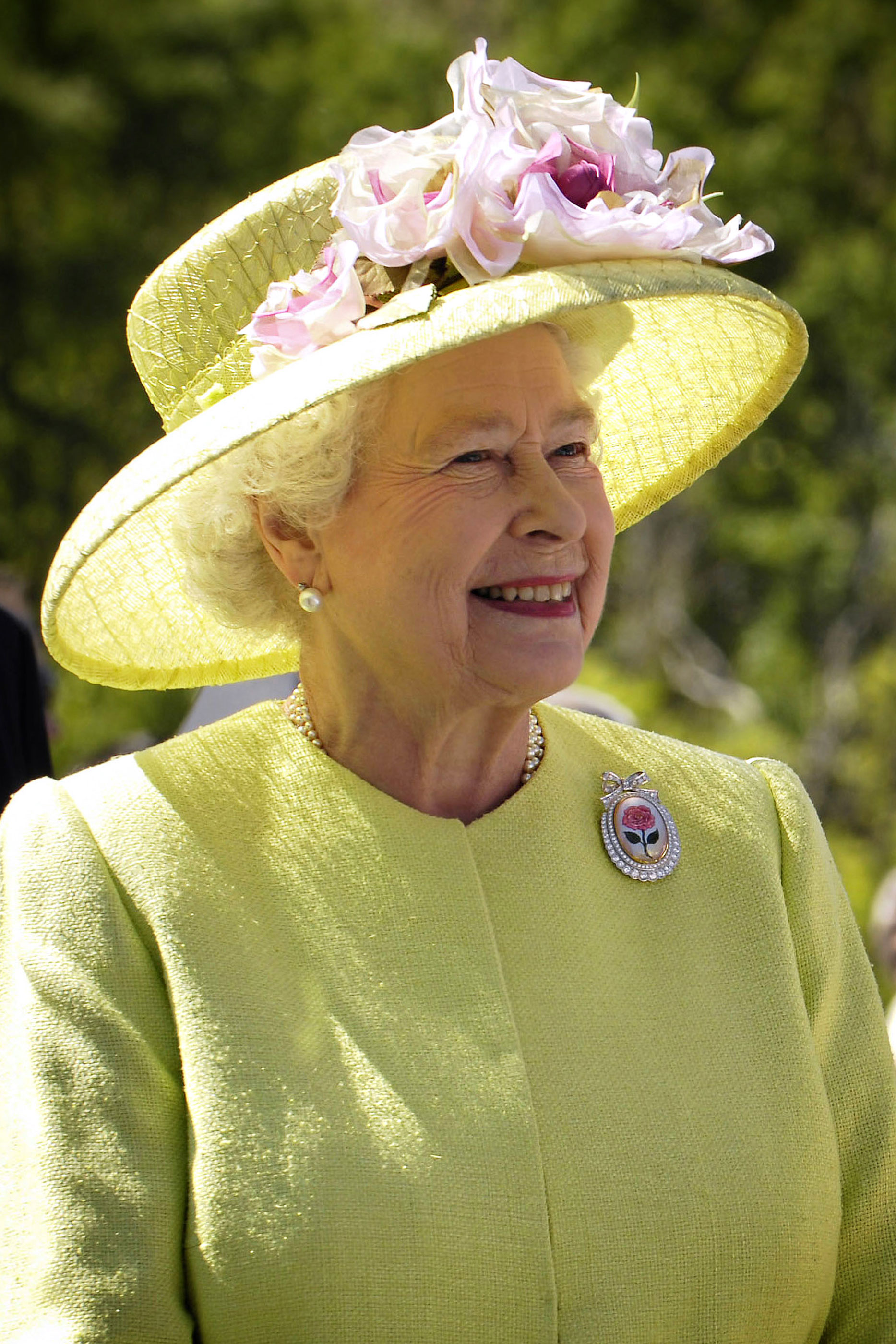 Rainha Isabel II com um vestido verde e um chapéu da mesma cor, com um pormenor dumas rosas na pala.