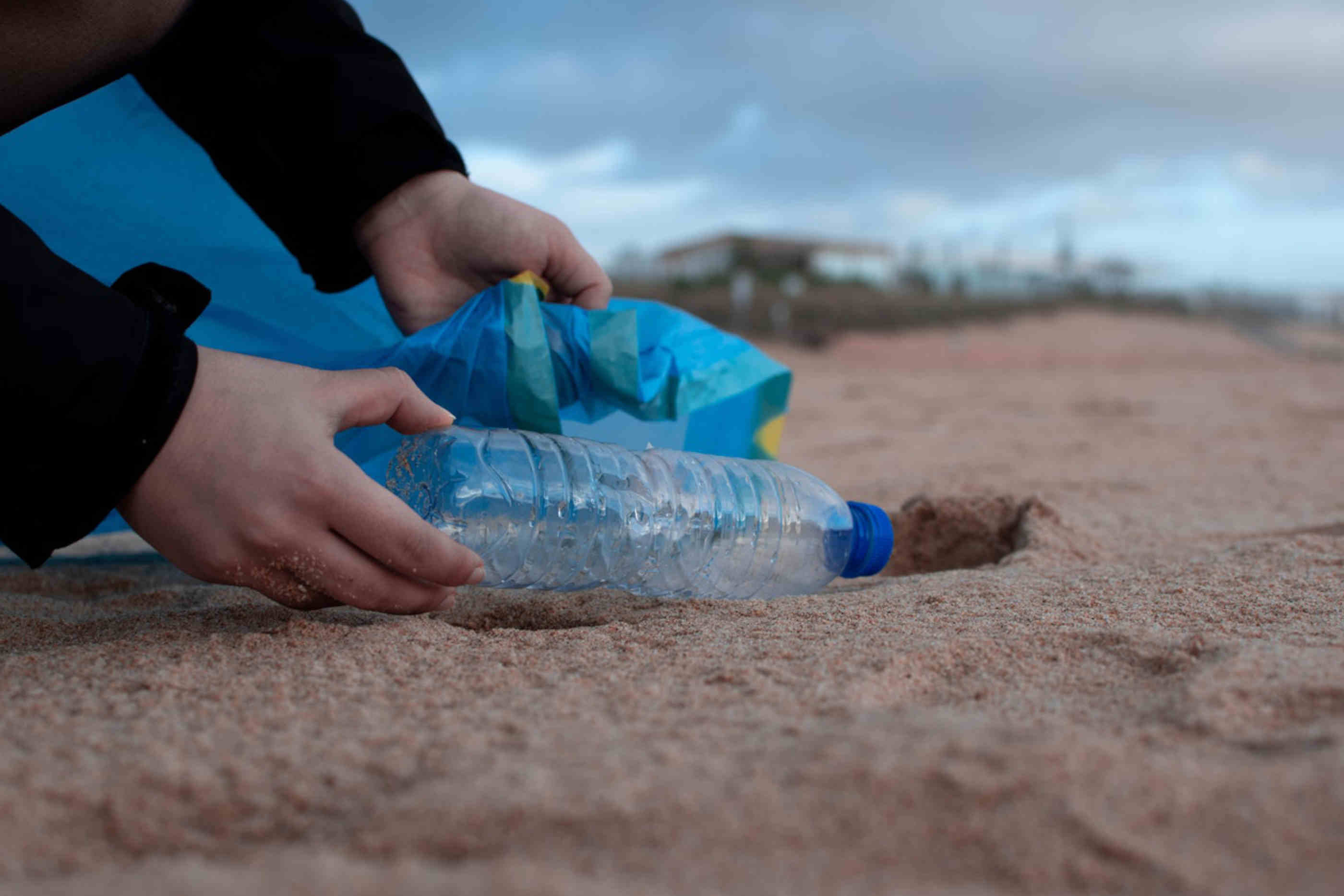 Pessoa colocando garrafa de agua no lixo