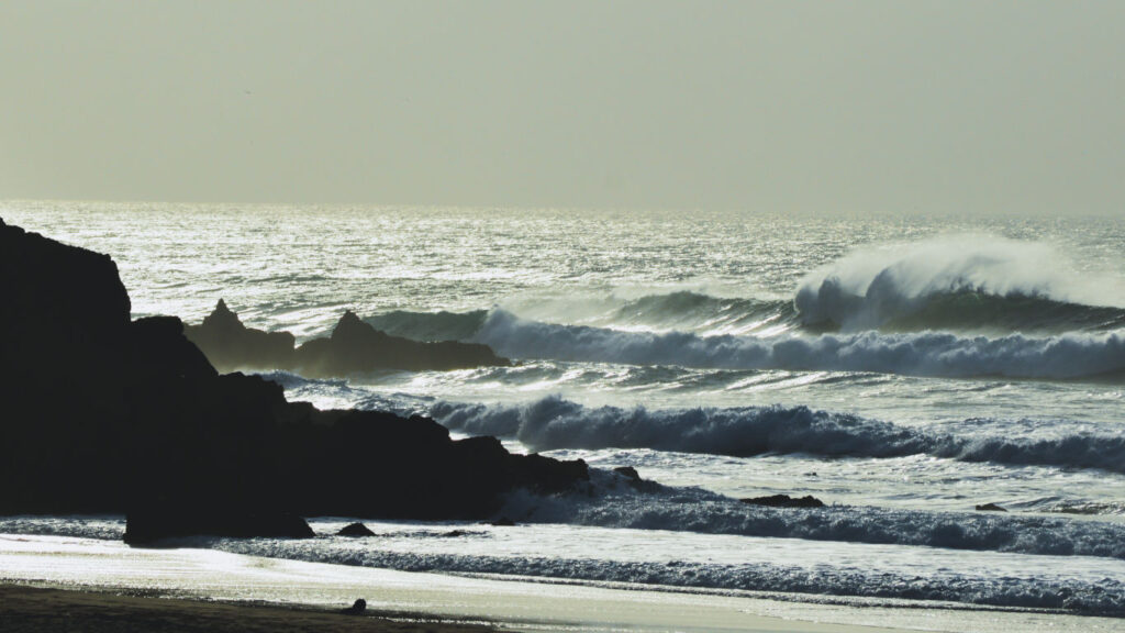 Ondas a baterem nas rochas ao pôr – do - sol