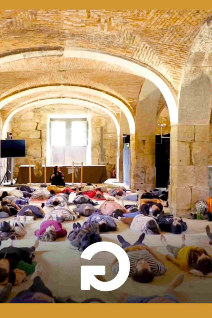 Conjunto de pessoas a meditar deitadas no chão no contexto de um workshop