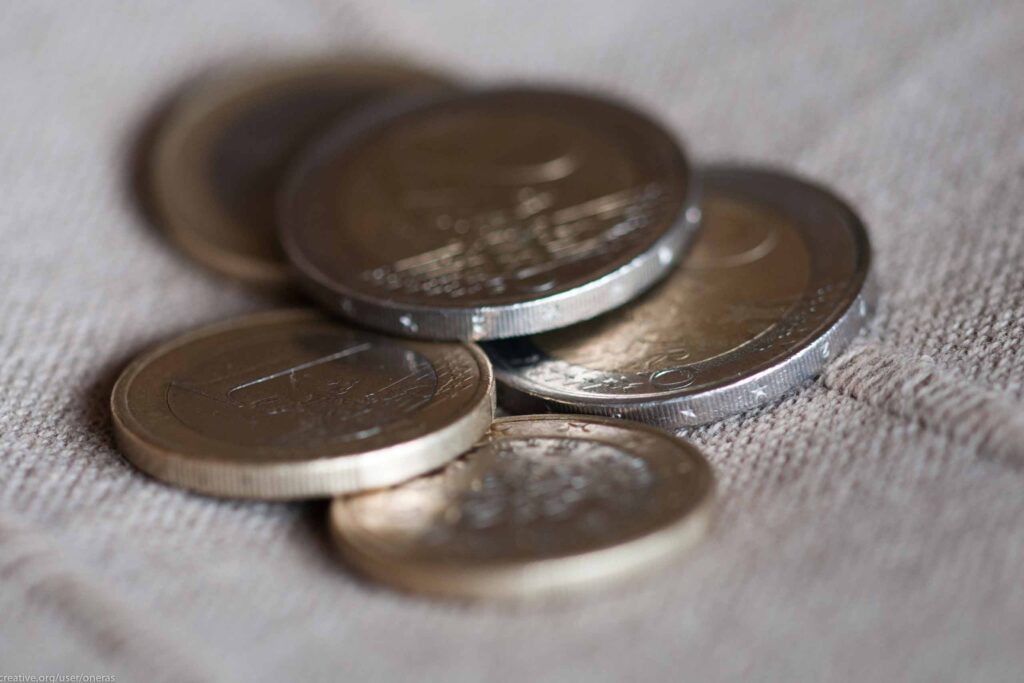 Cinco moedas de um e dois euros espalhadas num tecido.