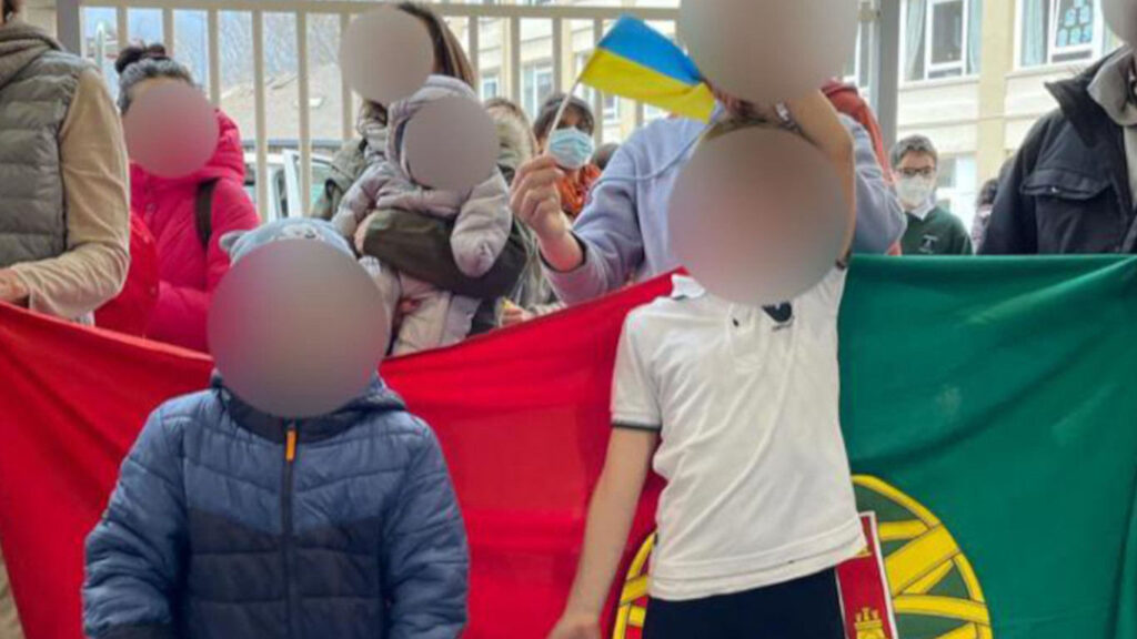 Crianças em frente à bandeira de Portugal.
