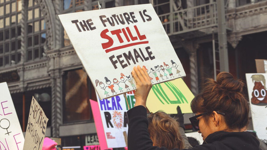 Uma mulher a segurar um cartaz numa manifestação feminista