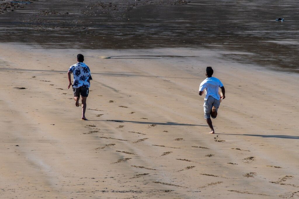 Dois homens correm na praia.