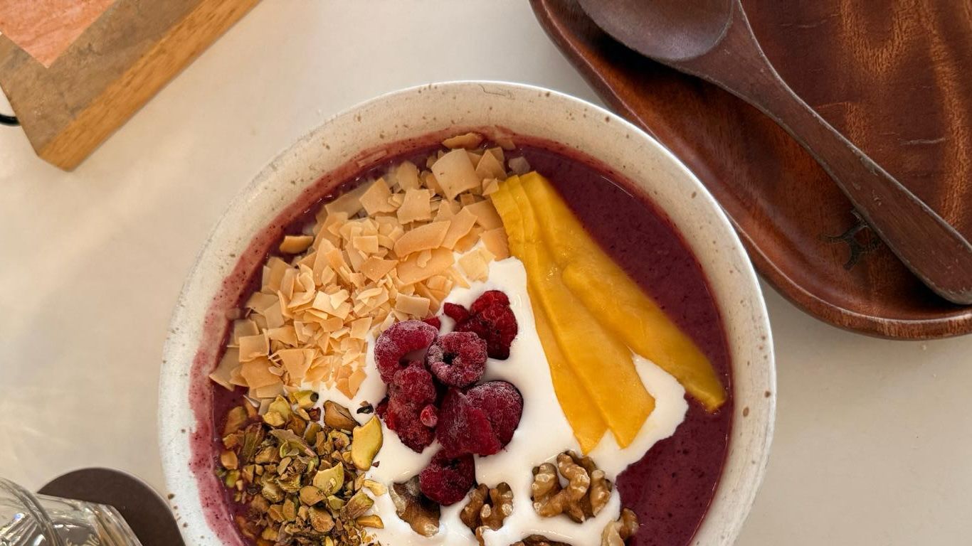 Tigela de brunch de açaí com iogurte, frutas (framboesa e manga) e frutos secos (noz e amêndoa)