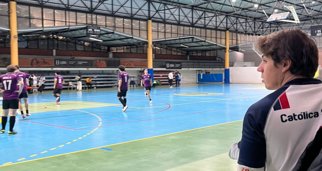 Jogador da Católica observa os seus colegas em ação num treino de futsal.