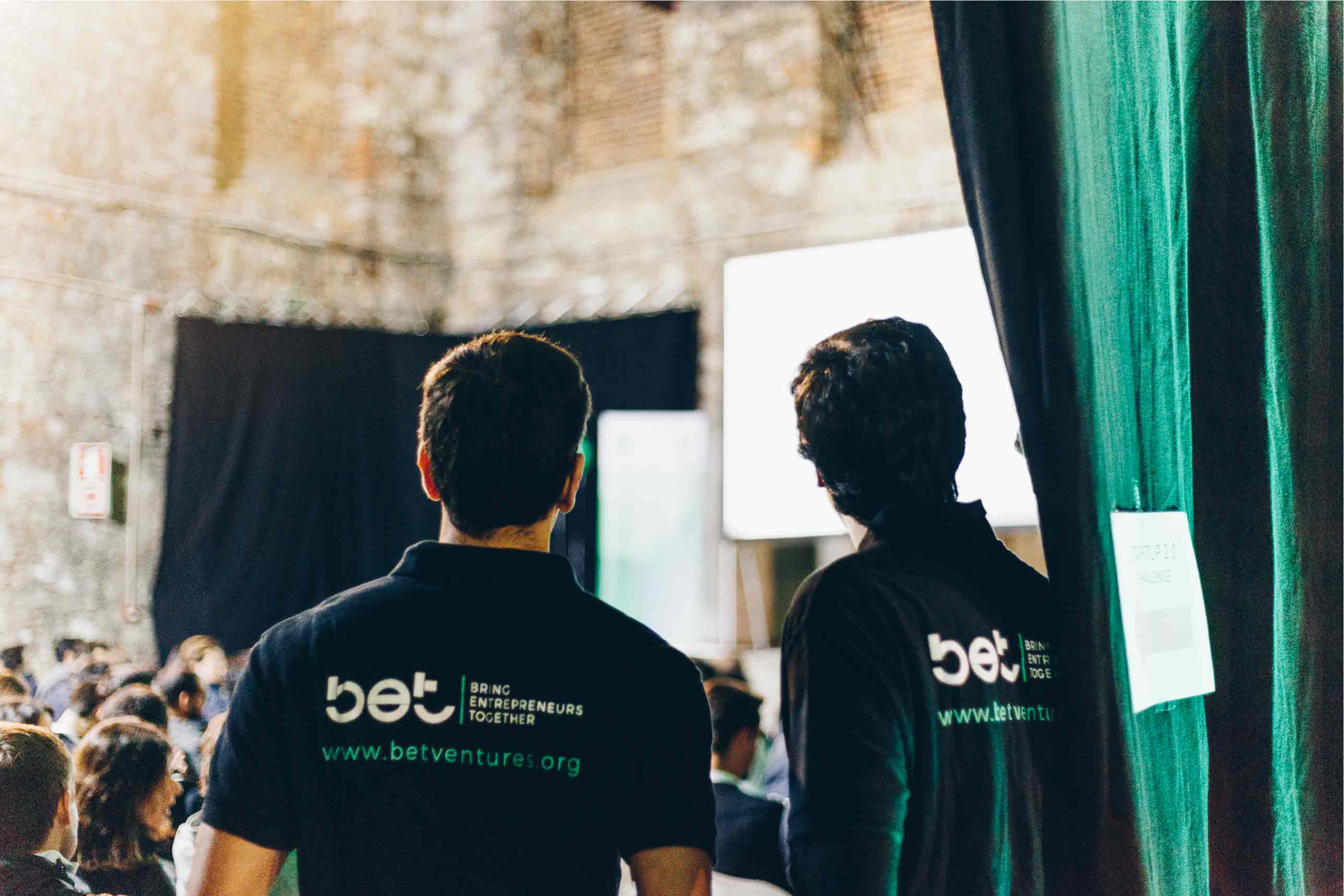 Dois jovens com polos do BET virados de costas a assistir a uma palestra durante o evento BET24
