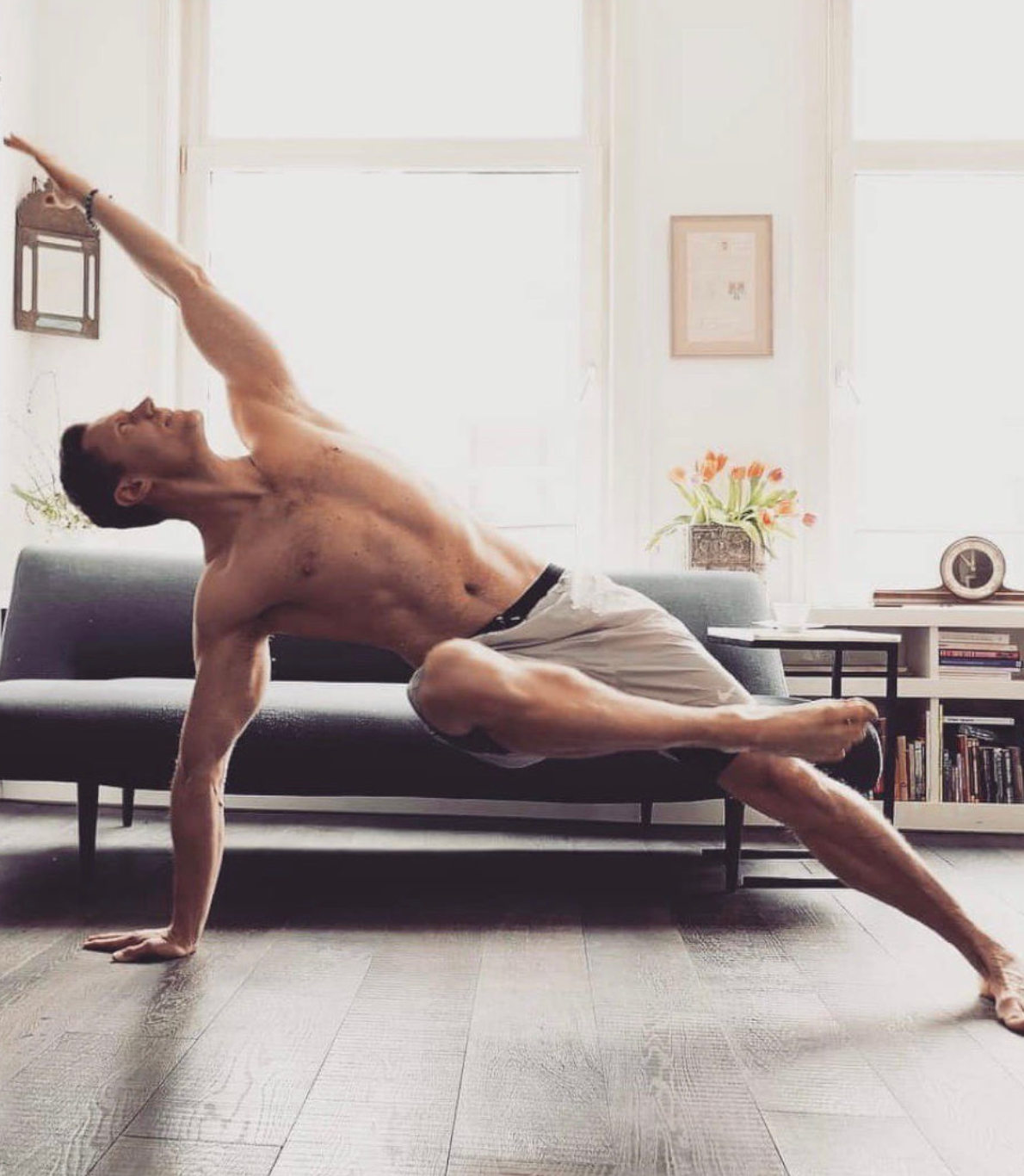 Miki Molnar, na sua sala, vestido com uns calções de desporto, faz um exercício de flexibilidade e equilíbrio, apoiando-se apenas com a mão direita e a perna a esquerda.