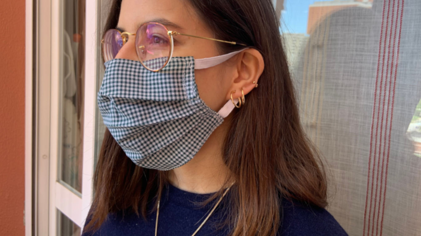 Rapariga a utilizar uma máscara de uso público a tapar o nariz e a boca