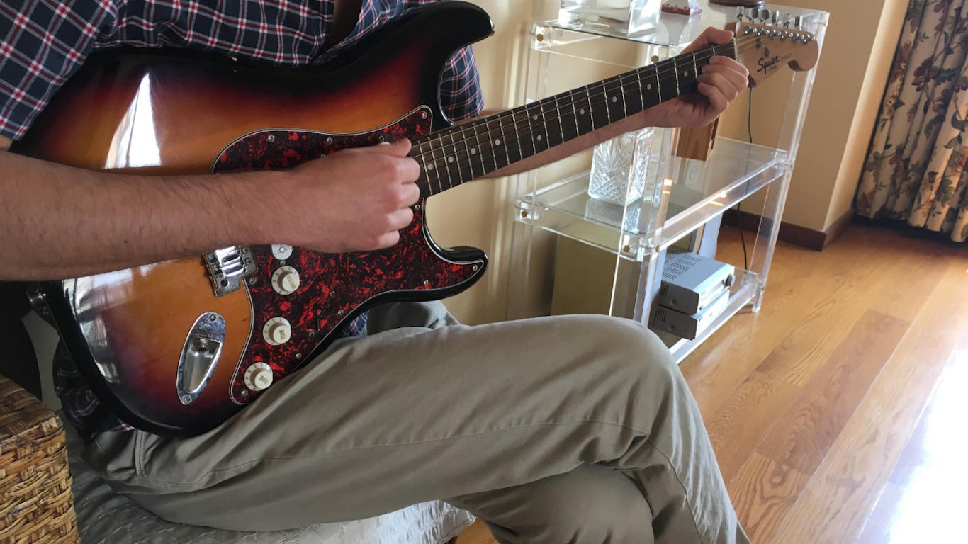 Rapaz a tocar guitarra elétrica castanha Stratocaster
