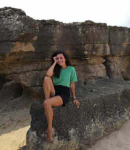 Mulher sentada em rochas na praia