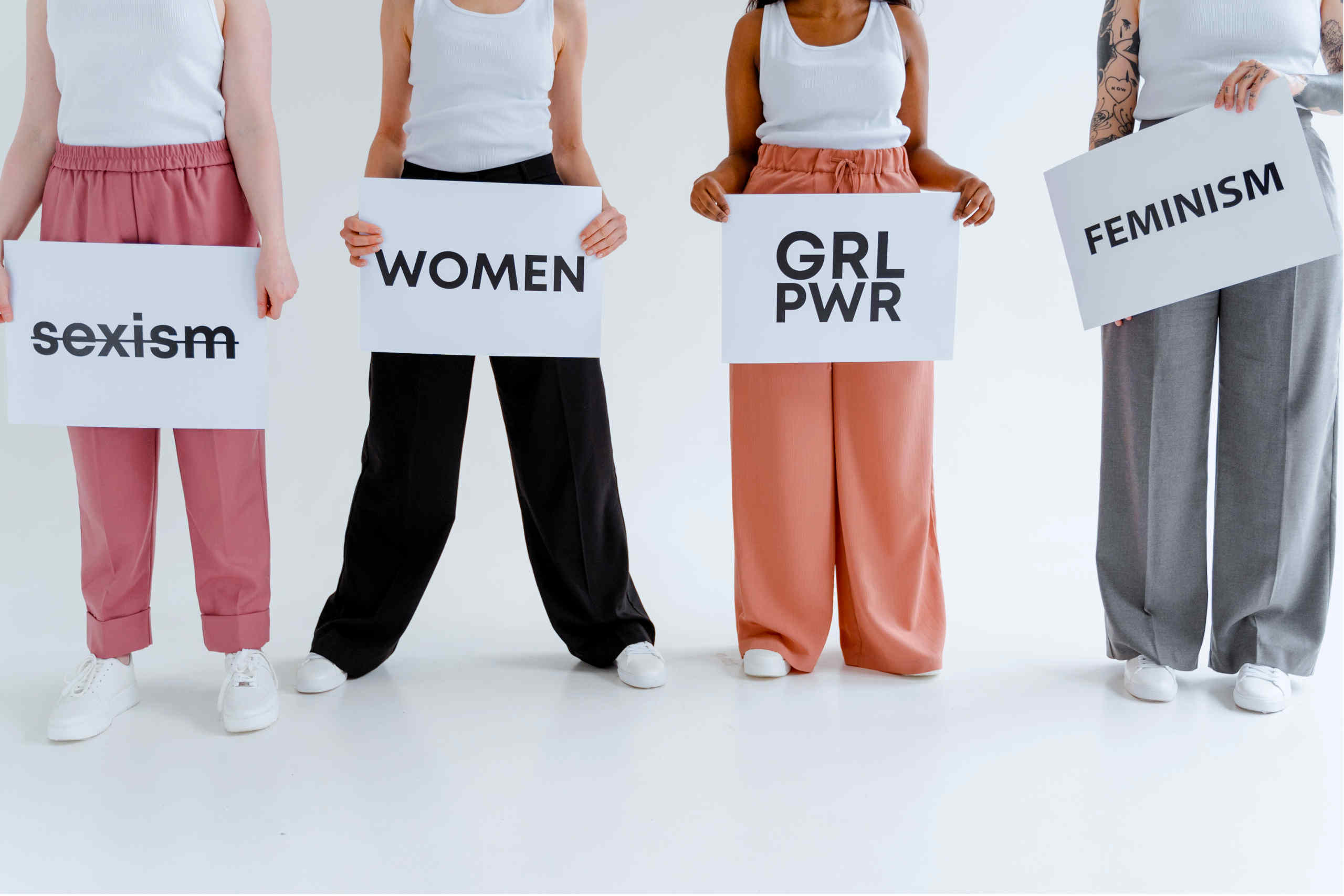 Quatro mulheres com cartazes com palavras relacionadas com o feminismo.