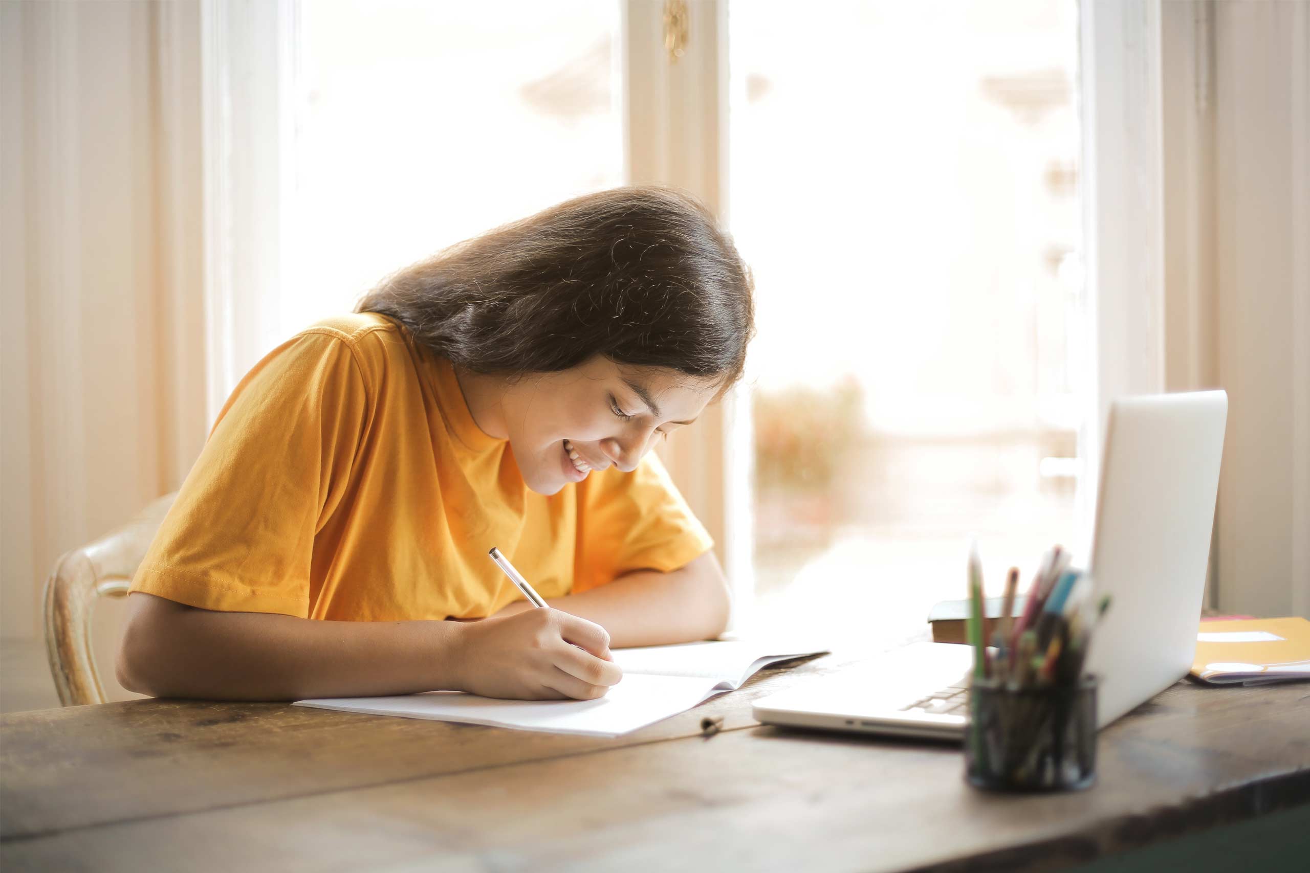 Jovem adolescente a escrever notas durante uma aula online