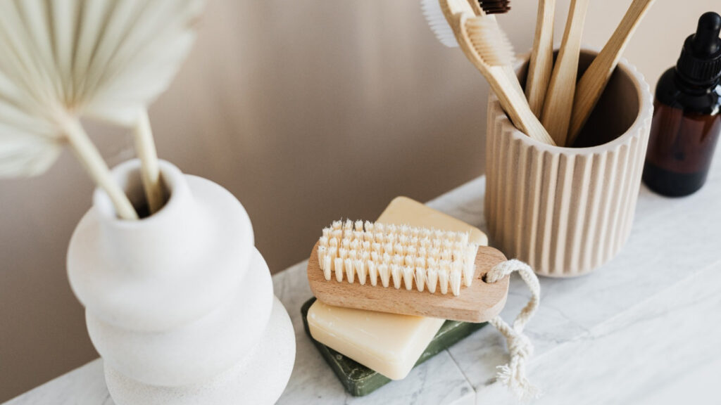 escova, sabonetes sólidos e copo castanho com escovas de bambú