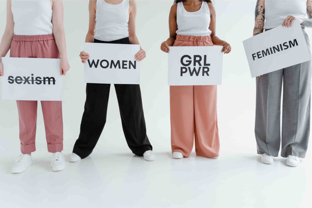 quatro raparigas a segurarem cartazes brancos com as palavras sexism, girl power, women e feminism
