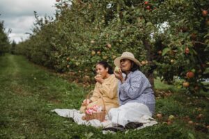 mulheres a comer maçãs num pomar